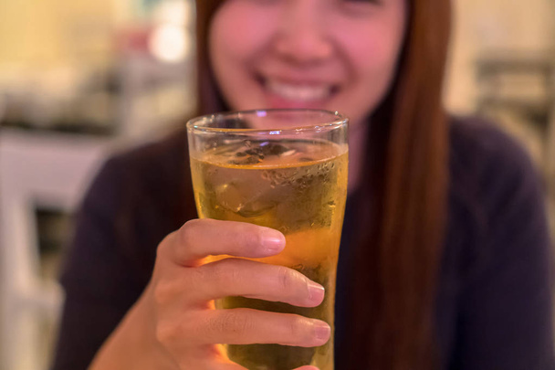 Asian young woman in happiness action and drinking beer in pub and restaurant with low light place, relax and drink concept - 写真・画像
