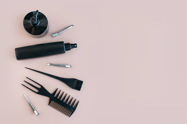 Flat lay Minimal composition with black hair salon tools on pastel background. Hair dye brush and bottle for Color Mixing. Tools for hair styling, dye and hairdye on beige background top view - Photo, image
