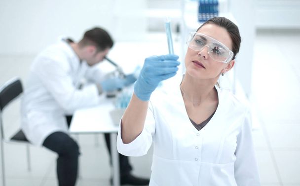 serious female scientist looks at the tube with the results of the analysis - Φωτογραφία, εικόνα