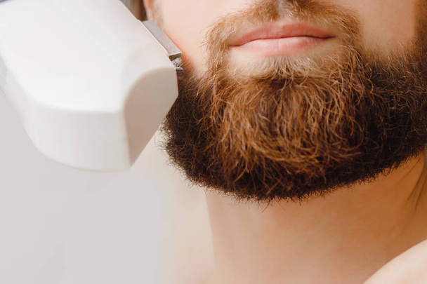 Male depilation laser hair removal beard and mustache procedure treatment in salon. - Photo, Image