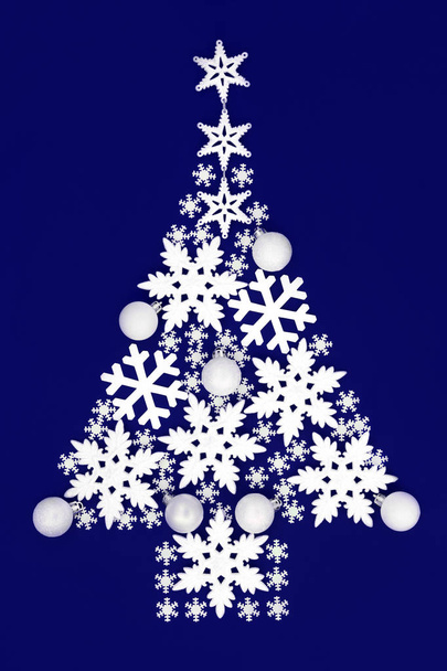 クリスマス ツリーは、白い雪の結晶を抽象化し、青の背景に安物の宝石装飾のラウンドします。ホリデー シーズンの伝統的なクリスマスのグリーティング カード. - 写真・画像