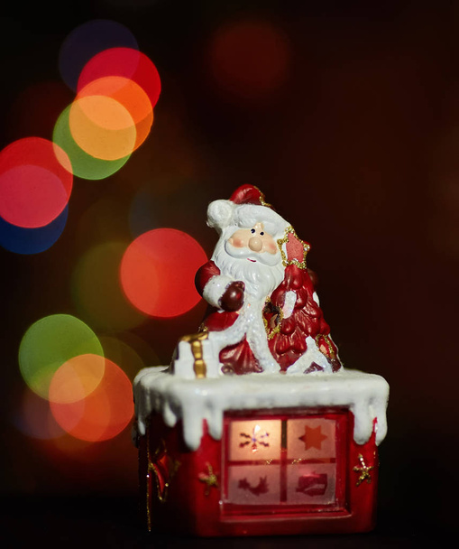 Statuetka Świętego Mikołaja robi ćwiczenia czekając na Boże Narodzenie. Kolorowy bokeh - Zdjęcie, obraz