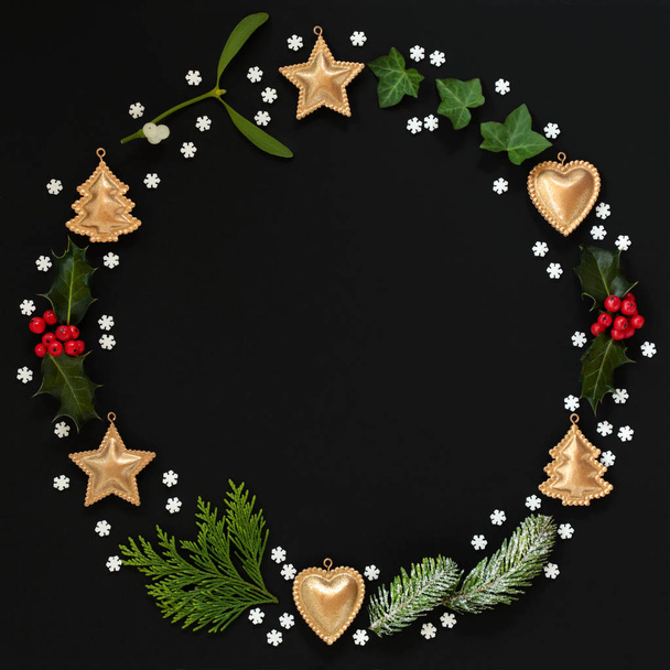 Μινιμαλιστική στεφάνι χριστουγεννιάτικο γιρλάντα με χειμώνα χλωρίδα, χρυσό μπιχλιμπίδι διακόσμηση και νιφάδες χιονιού σε μαύρο φόντο. Επίπεδη θέσει. Χριστουγεννιάτικη κάρτα για την εορταστική περίοδο. - Φωτογραφία, εικόνα