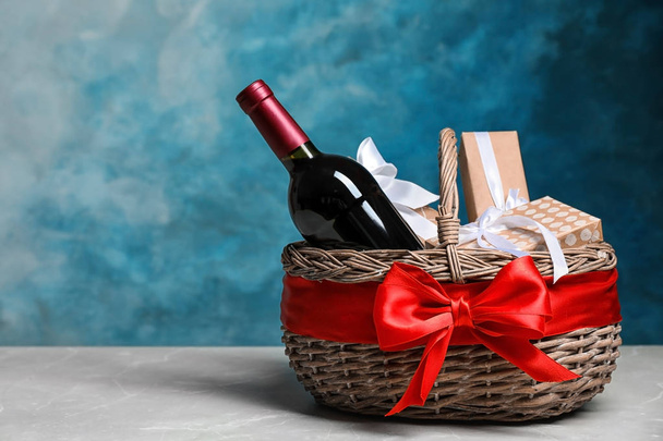 Подарунковий кошик з пляшкою вина на кольоровому фоні. Простір для тексту
 - Фото, зображення