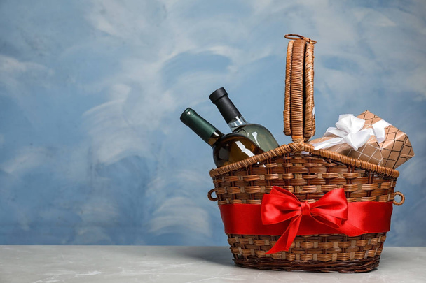 Gift basket with bottles of wine on color background. Space for text - Photo, Image