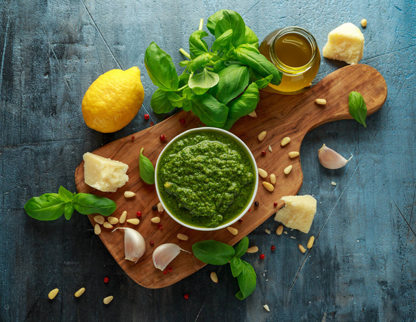 Pesto de albahaca verde con queso parmesano, piñones, ajo y limón sobre tabla de madera
 - Foto, imagen