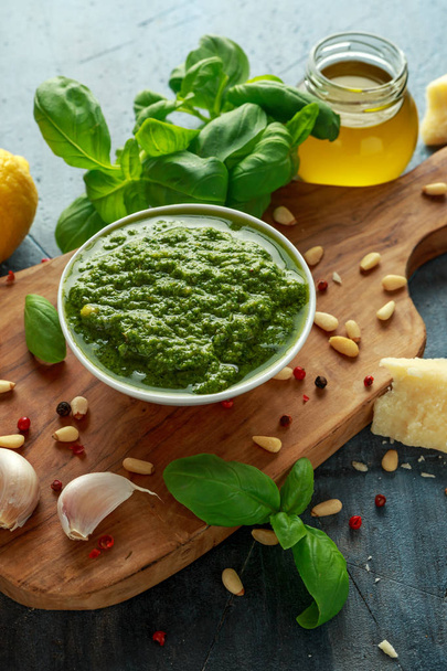 Yeşil fesleğen Pesto parmesan peyniri, çam fıstığı, sarımsak ve limon ahşap tahta üzerinde - Fotoğraf, Görsel