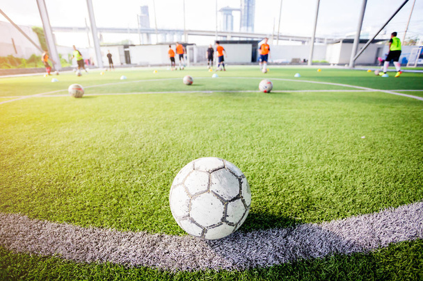 Fußball auf grünem Kunstrasen mit verschwommenen Fußballern trainiert. Fußball-Akademie. - Foto, Bild