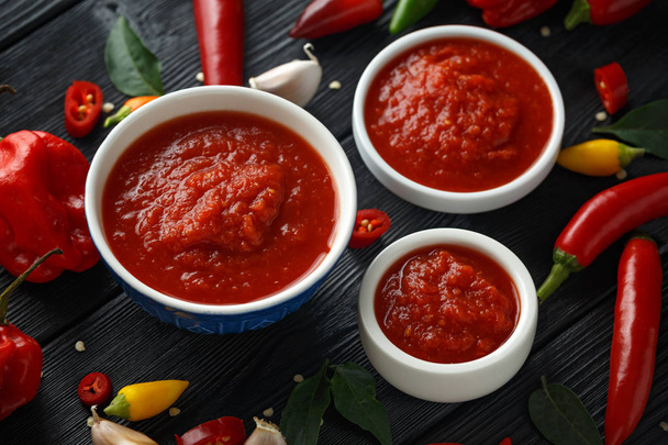 spicy hot sweet chili sauce with mix of chilli pepper, garlic and tomatoes on rustic wooden background - Photo, Image