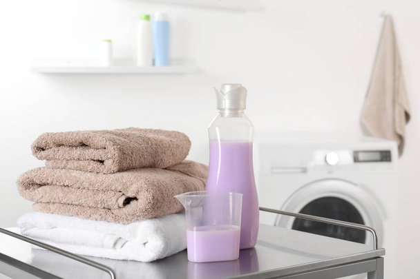 Pila di asciugamani puliti e detersivo sul tavolo in lavanderia. spazio per il testo
 - Foto, immagini