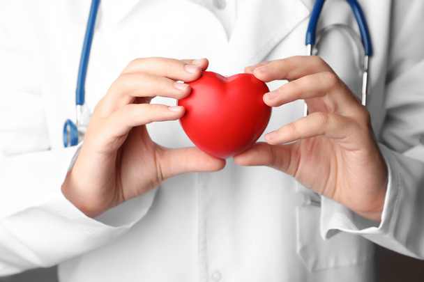 Doctor holding toy heart, closeup. Pulse checking - Photo, Image