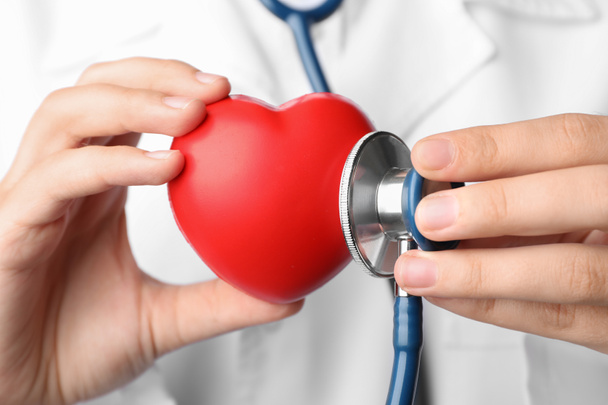 Médico segurando brinquedo coração e estetoscópio, close-up. Verificação de pulso
 - Foto, Imagem