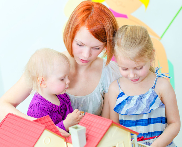 Дети и их мать играют в кукольный домик
 - Фото, изображение