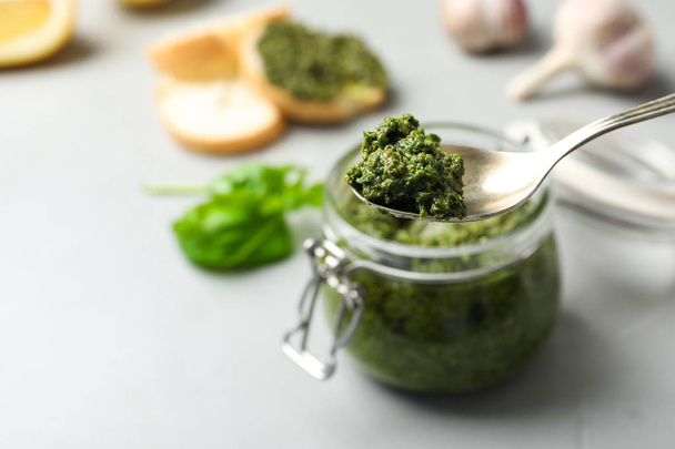 Spoon with basil pesto sauce and space for text on blurred background - Foto, immagini