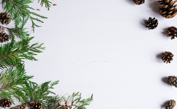 Új év összetétele. Keret a karácsonyfa és kúpok, egy fából készült fehér háttér a szöveghez. Új évi kedvezmények. Karácsonyi ünnepek - keret, a szöveg. Karácsonyi összetétele - Fotó, kép