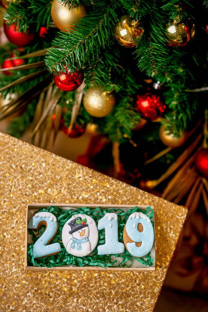 Cookie in the form of a numbers 2019 in carton box in front of decorated fir tree. Holiday sweets. New Year's and Christmas theme. Festive mood. Christmas card. - Foto, immagini