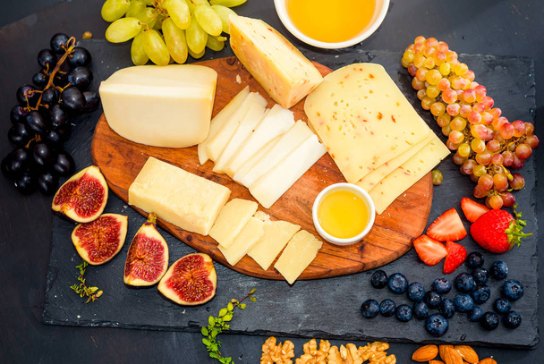 Cheese plate served with grapes, jam, figs, crackers and nuts - Фото, зображення