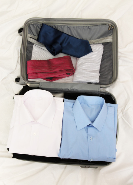 Open grey suitcase with clothing on bed - Φωτογραφία, εικόνα