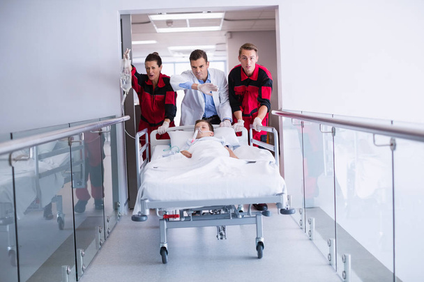 Artsen duwen noodgevallen brancard bed in gang in ziekenhuis - Foto, afbeelding