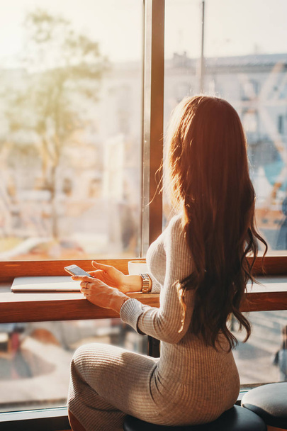 Giovane bella donna a un tavolo in caffè guarda la città attraverso la finestra
 - Foto, immagini