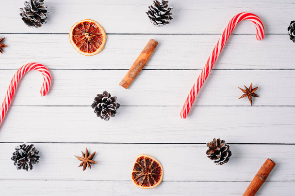 візерунок різдвяних цукерок, соснових шишок і сушених апельсинів на білому дерев'яному тлі. Новорічні прикраси
 - Фото, зображення