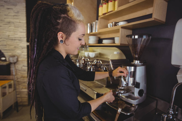 Waitress holding portafilter filled with ground coffee in cafe - Photo, Image