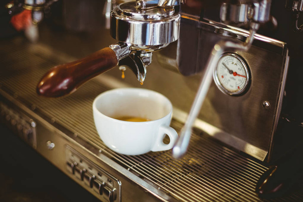 Primer plano del espresso que se vierte de la máquina de café en la cafetería
  - Foto, Imagen