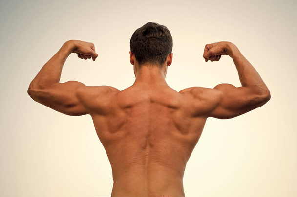 Man or sportsman flexing arms with fists, back view - 写真・画像