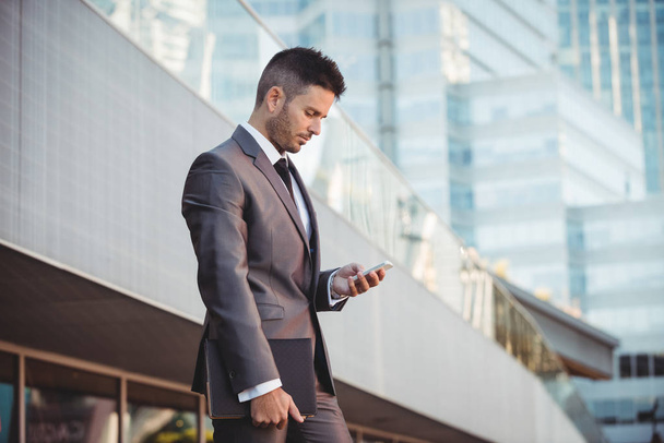 Businessman using mobile phone near office building - Photo, Image