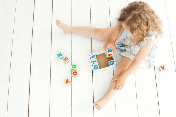 Roztomilá holčička hraje s abc kostky. Dítě studuje na neutrálním pozadí - Fotografie, Obrázek