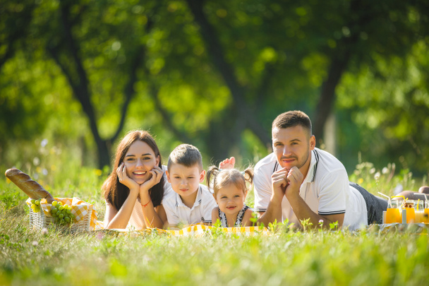Веселая семья устраивает пикник. Родители ужинают со своими детьми на открытом воздухе
. - Фото, изображение