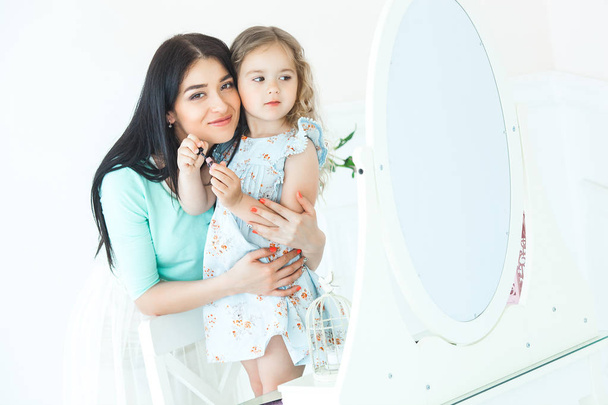 Młody piękny matka, patrząc w lustro z jej cute córeczka i uśmiecha się. Szczęśliwa rodzina pomieszczeniu - Zdjęcie, obraz