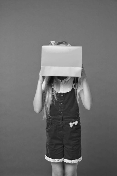 Blind of shopping. Kid holds package in front of face. Simple reminders how to shop smart. Girl cute teenager carries shopping bag. Kid bought clothing summer sale. Seasonal sale concept - Zdjęcie, obraz