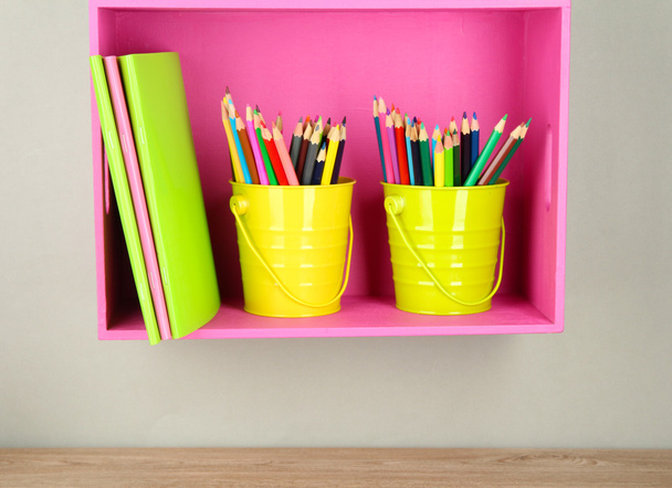 Colorful pencils in pails on shelf on beige background - Фото, изображение