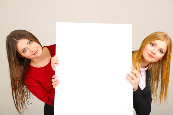 Two business women with blank form on grey background - Fotoğraf, Görsel