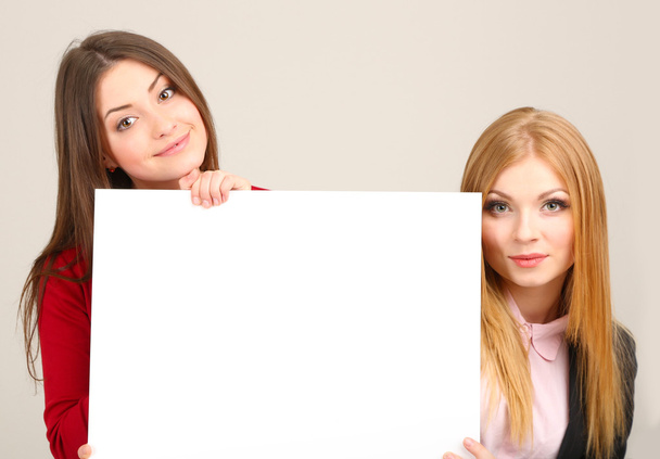 Two business women with blank form on grey background - Photo, image