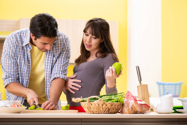 Man and pregnant woman preparing salad in kitchen  - Fotó, kép