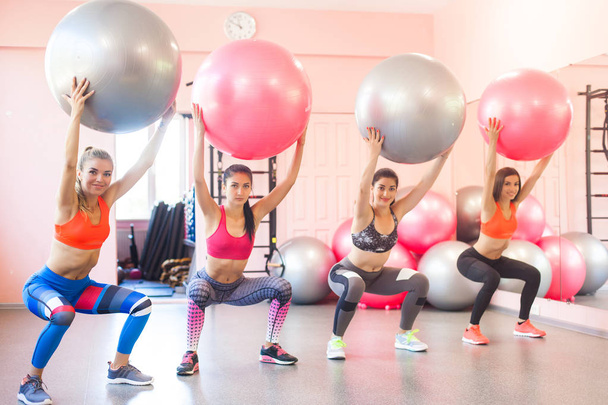 Ομάδα νεαρών γυναικών κάνει ασκήσεις με fitballs. Ζεύγος ασκήσεις για φυσική κατάσταση - Φωτογραφία, εικόνα