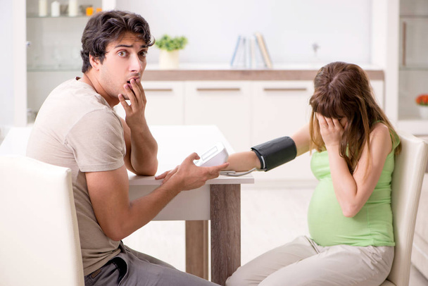 Marido verificando grávidas esposas pressão arterial
 - Foto, Imagem