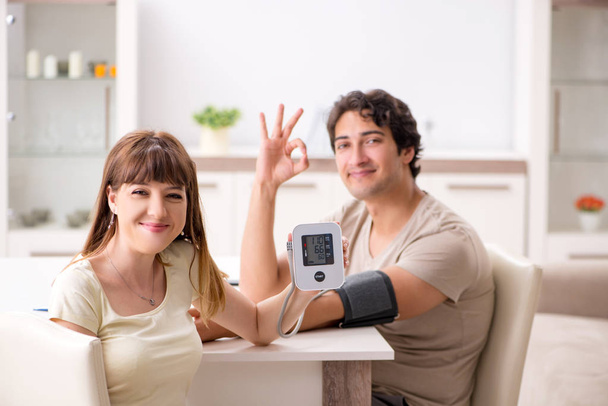 A férj vérnyomását ellenőrző feleség   - Fotó, kép