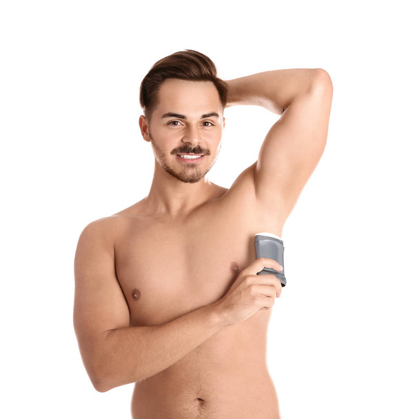 Young man using deodorant on white background - Photo, image