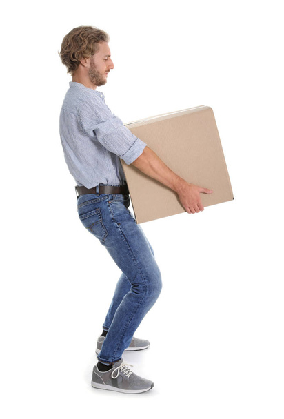 Full length portrait of young man carrying heavy cardboard box on white background. Posture concept - Valokuva, kuva