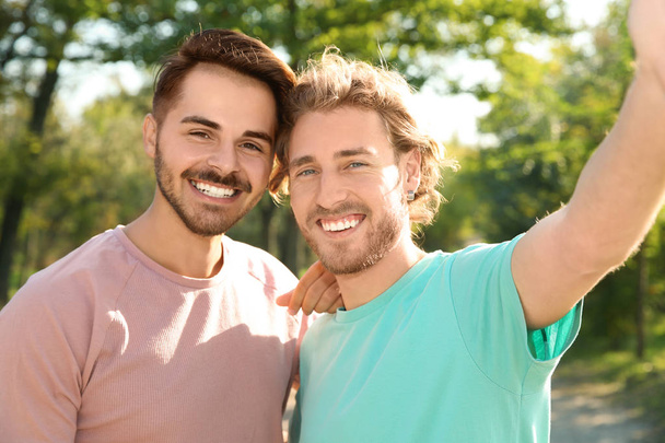 Portrait of happy gay couple smiling in park - Fotoğraf, Görsel