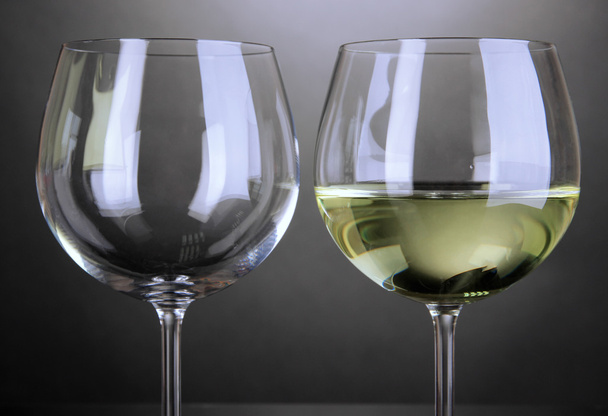 Empty and full wine glass on grey background - 写真・画像
