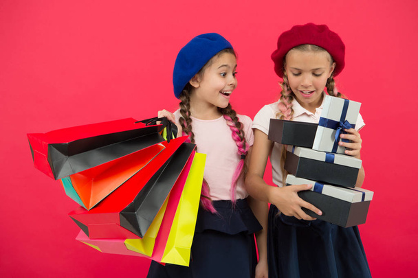 Shopping become fun with best friends. Children satisfied by shopping red background. Obsessed with shopping and clothing malls. Shopaholic concept. Kids cute schoolgirls hold bunch shopping bags - Fotoğraf, Görsel