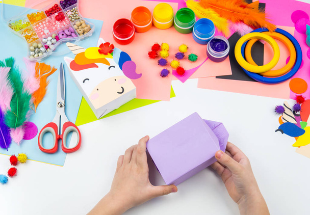 Child sticks hand craftwork unicorn. Unusual gift from paper box. Master class handmade. Favorite hobby. Kindergarten and school. - Foto, imagen