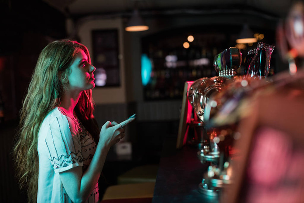 Красива жінка використовує мобільний телефон за лічильником в барі
 - Фото, зображення