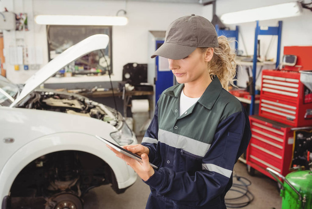 Female mechanic using digital tablet in repair shop - Photo, Image