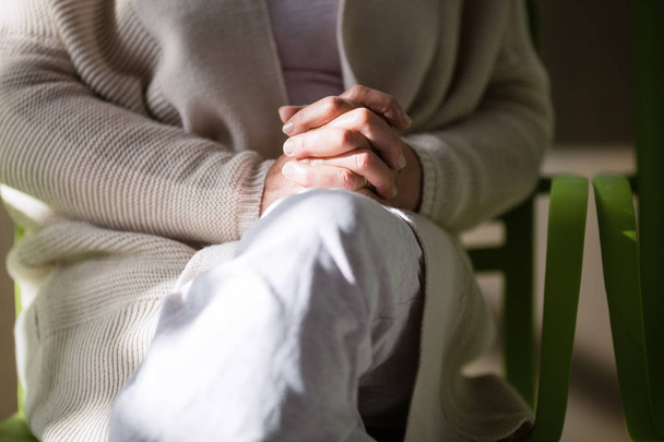 Середина літньої жінки сидить з застібнутими руками
  - Фото, зображення