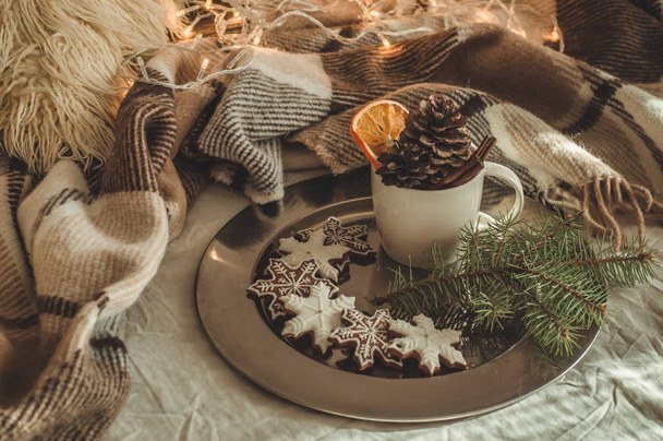 Κύπελλο με κώνους και ξηρό πορτοκαλί με ΑΣΤΡΑΚΙ, κλαδί έλατου, χριστουγεννιάτικα μπισκότα, ζεστή κουβέρτα πλεκτό, νέο έτος, Χριστούγεννα ακόμα ζωή. - Φωτογραφία, εικόνα
